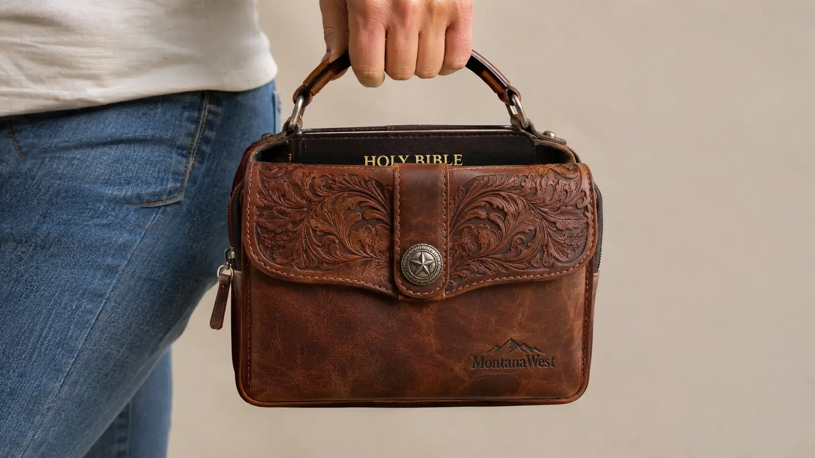 A hand holding the Montana West Bible cover by its handle, Bible inside, ready to carry